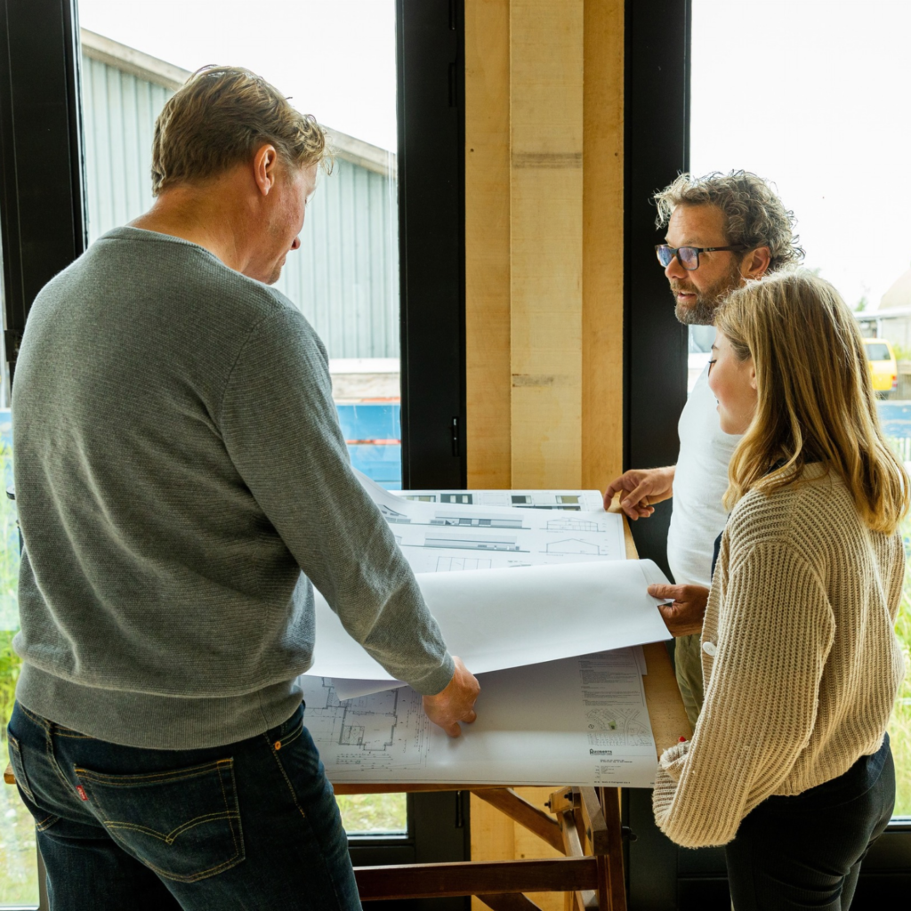 Drie mensen die staand samen een TunHûs aan het voorbespreken zijn